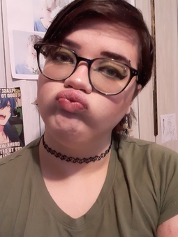 a picture of ezra, the creator of this blog. they are a nonbinary person with dark brown hair and blue-green eyes. they are wearing green eyeshadow and have graphic eyeliner and pink lip gloss on.
